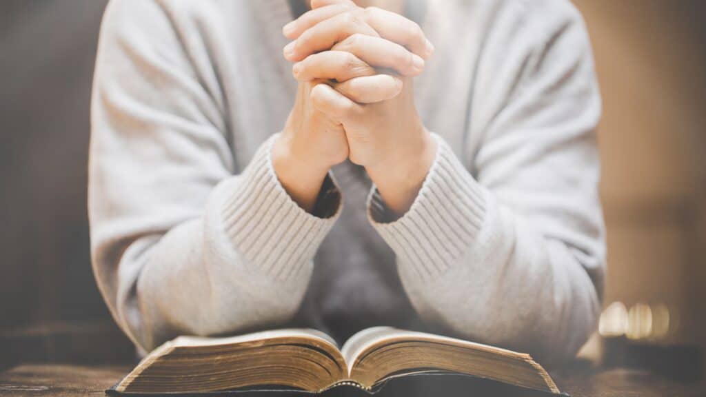 front view of a person praying over an open Bible