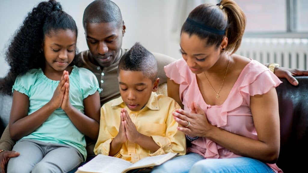 a family of four praying together