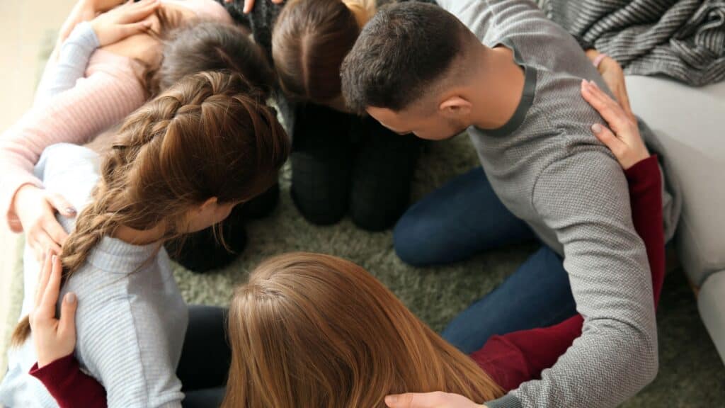 a group of people in a huddle praying together