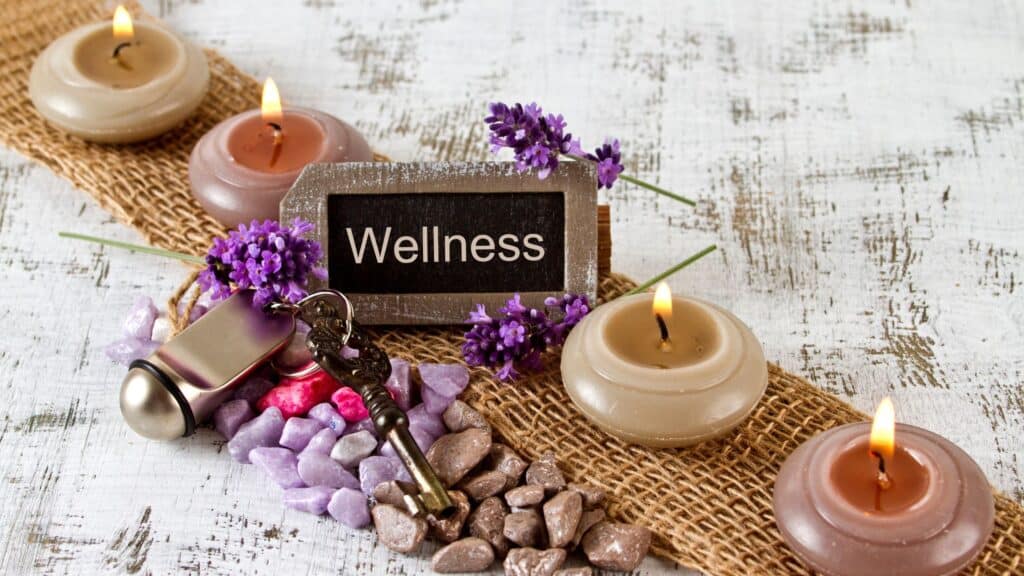 the word wellness written on a small chalkboard next to spa candles
