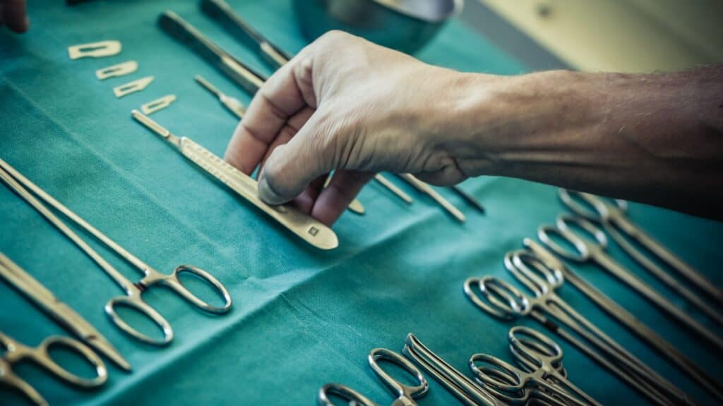 a hand picking up surgical instruments